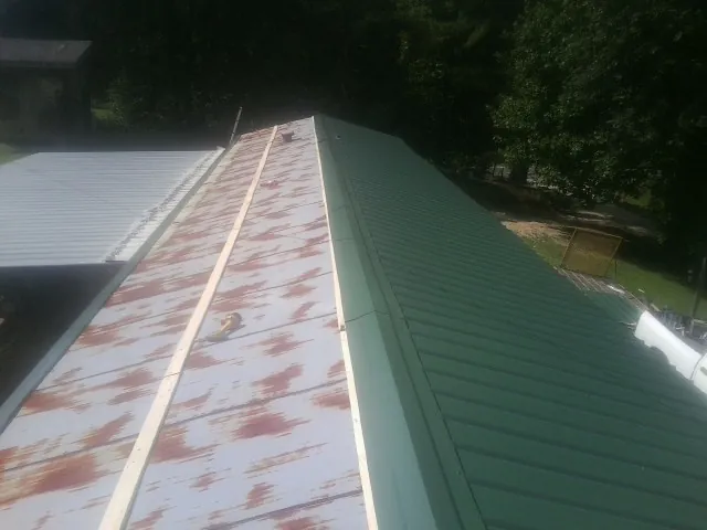 Old rusted panels beside newly installed green metal roofing — Wind Damage Roof Repair by Roofing Brothers in Parkers Prairie