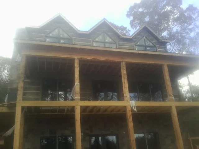 Dormers and porch framing on a large log home under construction — Roof Coating work by our crew in Parkers Prairie