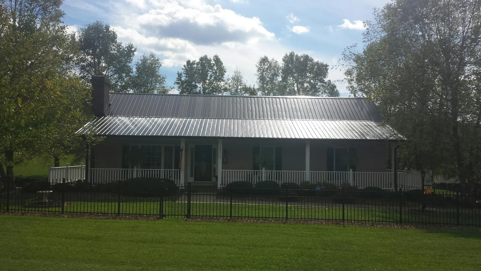 Gray metal roof on a brick ranch with a full width front porch — Gutter Guard Installation work by our crew in Parkers Prairie