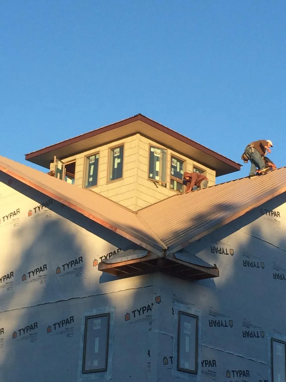 Roofers working around a rooftop cupola on a new metal roof at sunset — Roof Waterproofing in Parkers Prairie by Roofing Brothers